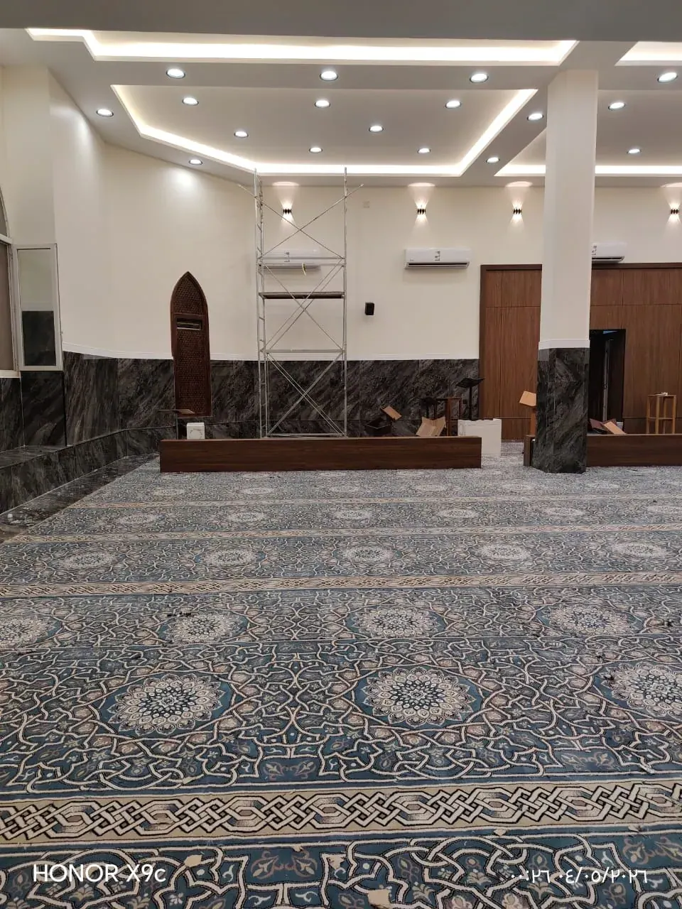 قاعة صلاة كبيرة مفروشة بسجاد بنقوش ميداليات زرقاء بعد التجديد