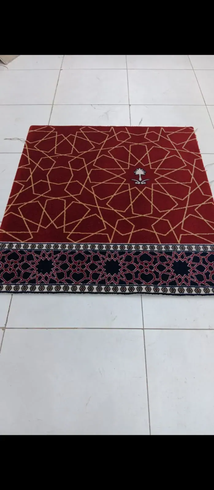 سجاد مسجد أحمر بخطوط ذهبية وإطار زخرفي يُفحص قبل الاعتماد