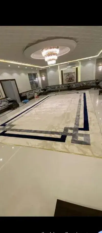 سجادة صالة بحدود هندسية داكنة على رخام لامع تحدد منطقة الجلوس